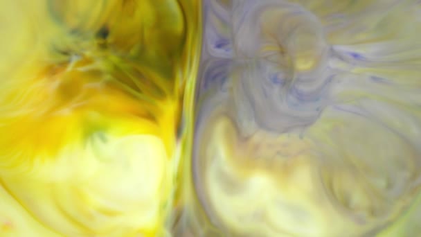 Inchiostro in acqua. Inchiostro giallo e viola che reagisce in acqua creando uno sfondo astratto . — Video Stock