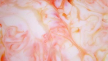 4K görüntü. Suda mürekkep. Kırmızı ve turuncu mürekkep suda reaksiyona girerek soyut bir arkaplan oluşturuyor.