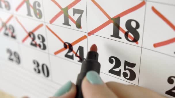 La mano femminile attraversa con il marcatore rosso il giorno del calendario 25. Colpo lento. Da vicino. — Video Stock