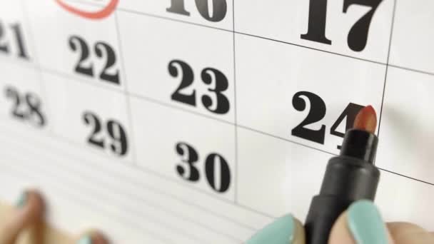 Vrouwelijke hand omcirkelt met rode stift de kalenderdag 24. Slow motion schot. Sluiten. — Stockvideo