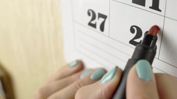 Vrouwelijke hand omcirkelt met rode stift de kalenderdag 28. Slow motion schot. Sluiten. — Stockvideo