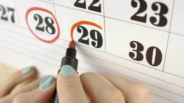 Mano femminile circonda con marcatore rosso il giorno del calendario 29. Colpo lento. Da vicino. — Video Stock