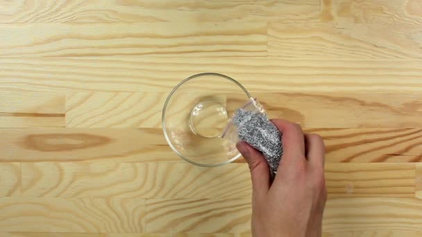 女性はガラスのボウルに銀砂糖のスプリンクルドットを注ぐ,トップビュー — ストック動画