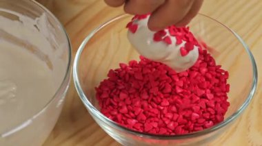 Bir kadın kalp pastası serpiyor, kırmızı sargılı, yakın.