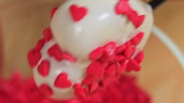 Bir kadın kalp pastası serpiyor, kırmızı sargılı, yakın.