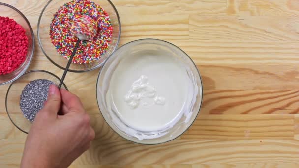 A woman sprinkles cake pops with colored dressing, top view — Stock Video