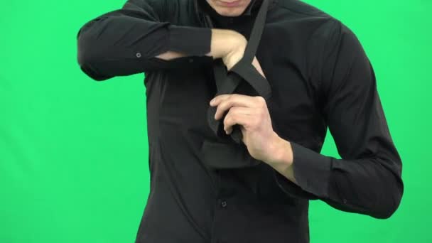 Chlápek v černé košili si váže černou kravatu na zelenou. — Stock video