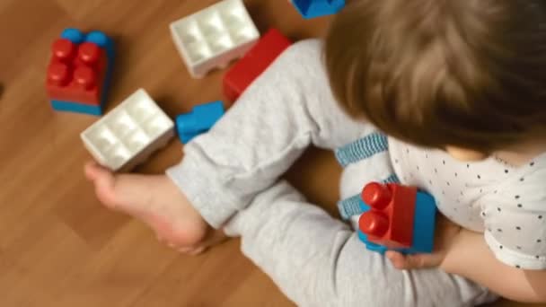Το παιδί παίζει με το κιτ σχεδιαστών στο πάτωμα, κορυφαία άποψη — Αρχείο Βίντεο