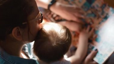 Kollarında çocuk olan anne büyük bir kitap oynuyor, kapat.