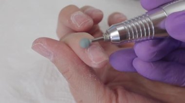 Genç bir kadın manikür makinesiyle tırnak cilasını temizliyor.