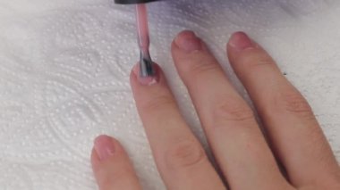 Genç bir kadın tırnaklarını doğal pembe jel bazlı boyuyor. Manikür. Ellerini kapat.