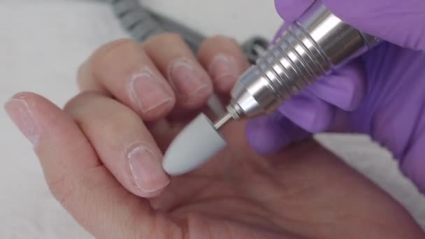 Young woman removes gel shellac polish from nails using manicure machine, close up shot — Stock Video