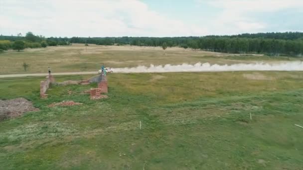 Desyatyny, Ucrânia - 8 de julho de 2018: Vista aérea. Carro de rali passa seção de cascalho da pista perto da aldeia, deixa para trás uma trilha de poeira — Vídeo de Stock