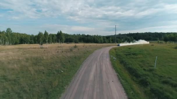 Desyatyny, Ukraina - 8 lipca 2018: Widok z lotu ptaka. Samochód rajdowy przechodzi żwirowy odcinek toru w pobliżu wsi, pozostawia za sobą ślad kurzu — Wideo stockowe