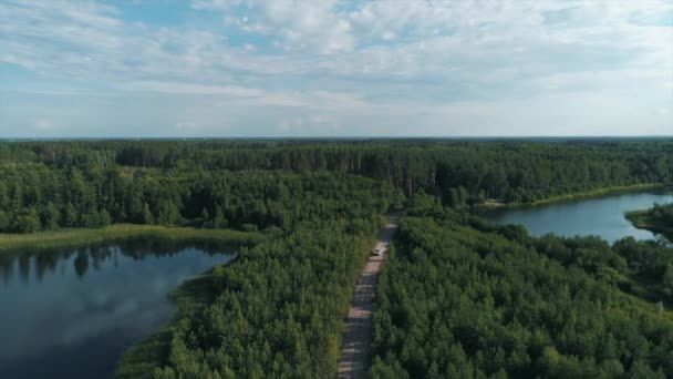 Desyatyny,ウクライナ- 2018年7月8日:航空写真。ラリーカーは村の近くのトラックの森林セクションを通過し、ほこりの歩道の後ろに残します — ストック動画