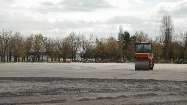 Kijów, Ukraina - 15 kwietnia 2020: Wałek drogowy przygotowuje powierzchnię do budowy stadionu. Szeroki strzał. — Wideo stockowe