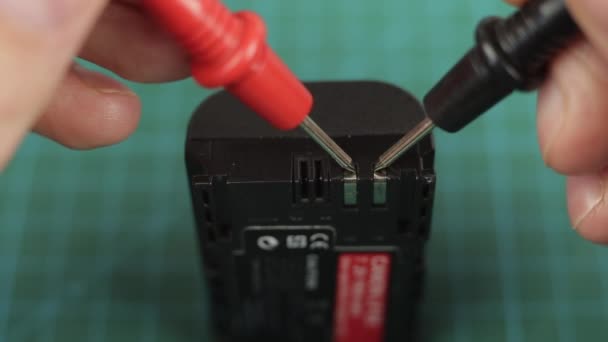 Multímetro electrónico herramienta de medición de voltaje en la batería de litio. De cerca. — Vídeos de Stock