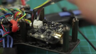 FPV yarış araçlarını cımbız kullanarak monte eden genç adamların aşırı yakın çekimi. Pin bağlanıyor