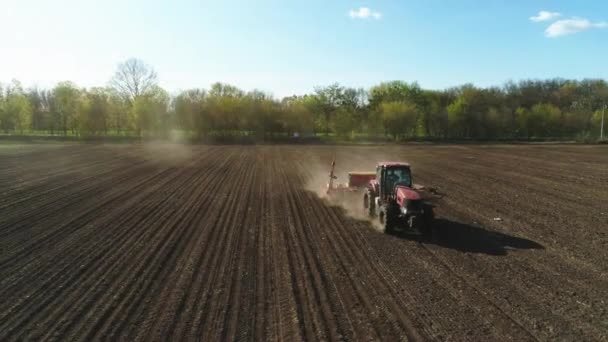 Vista aérea del tractor que trabaja en el campo de polvo con una moderna máquina de semillas de siembra en un campo recién arado. Plantación de semillas mecanización . — Vídeos de Stock