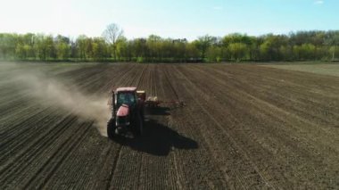 Tarlada çalışan traktörün hava görüntüsü yeni sürülmüş bir tarlada modern bir tohum ekme makinesiyle. Tohum ekme mekanizasyonu.