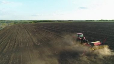 Tarlada çalışan traktörün hava görüntüsü yeni sürülmüş bir tarlada modern bir tohum ekme makinesiyle. Tohum ekme makineleşmesi. 27 Nisan 2020 Vitachiv, Ukrayna