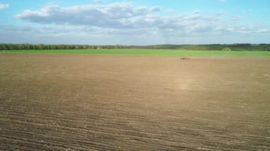 Tarlada çalışan traktörün hava görüntüsü yeni sürülmüş bir tarlada modern bir tohum ekme makinesiyle. Tohum ekme makineleşmesi. 27 Nisan 2020 Vitachiv, Ukrayna