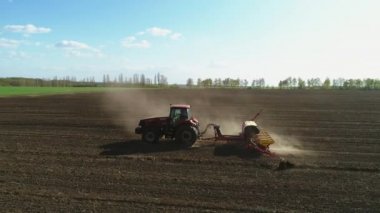 Vitachiv, Ukrayna - 23 Nisan 2020: Yeni sürülmüş bir tarlada modern bir tohum ekme makinesi ile tarlada çalışan traktörün havadan görünüşü. Tohum ekme mekanizasyonu.
