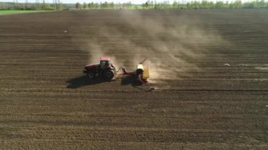 Vitachiv, Ukrayna - 23 Nisan 2020: Yeni sürülmüş bir tarlada modern bir tohum ekme makinesi ile tarlada çalışan traktörün havadan görünüşü. Tohum ekme mekanizasyonu.