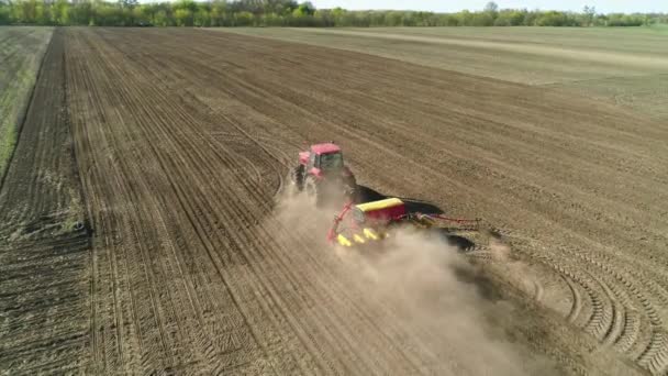 在一个新耕作的田里，用现代播种机在田里干活的拖拉机的空中景象。种植种子机械化. — 图库视频影像