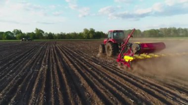 Tarlada çalışan traktörün hava görüntüsü yeni sürülmüş bir tarlada modern bir tohum ekme makinesiyle. Tohum ekme makineleşmesi. 27 Nisan 2020 Vitachiv, Ukrayna