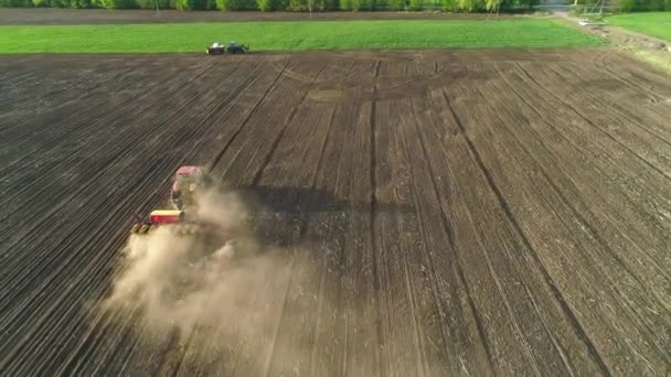 新しく耕されたフィールド内の近代的な播種種マシンで現場で働くトラクターの空中ビュー。種子の機械化を植える。2020年4月27日ウクライナ,ビタチフ — ストック動画