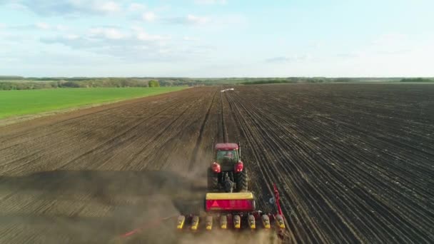 新しく耕されたフィールド内の近代的な播種種マシンで現場で働くトラクターの空中ビュー。種子の機械化を植える。2020年4月27日ウクライナ,ビタチフ — ストック動画