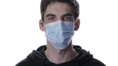 Tıbbi maskesini çıkarıp beyaz bir arkaplanda gülümseyen genç bir adamın portresi, covid-19 'u izole et.