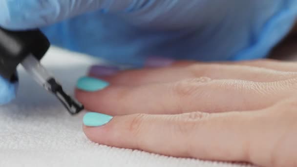 Young woman paints her nails with protective layer base. Nails manicure. — Stock Video