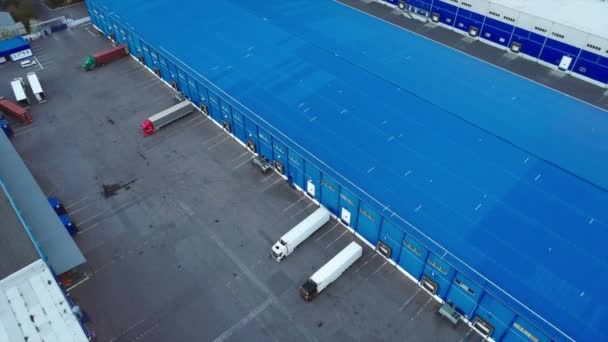 Bovenaanzicht vanuit de lucht van het grote logistieke park met magazijn met enkele opleggers vrachtwagens. — Stockvideo