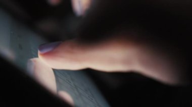 Karanlık bir odada genç bir kadının ellerini tabletin dokunmatik ekranına yazı yazmak için kapat.