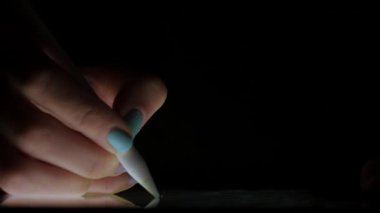 Karanlık odada ışıksız kalemle dijital tablete resim çizen sanatçının elini kapat.