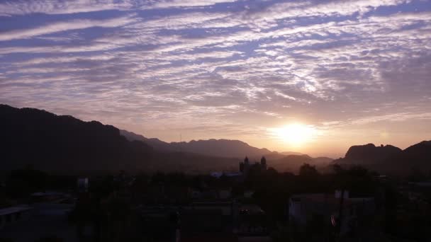 Sol de la mañana detrás de un encantador pueblo forestal; luz púrpura con nubes — Vídeo de stock