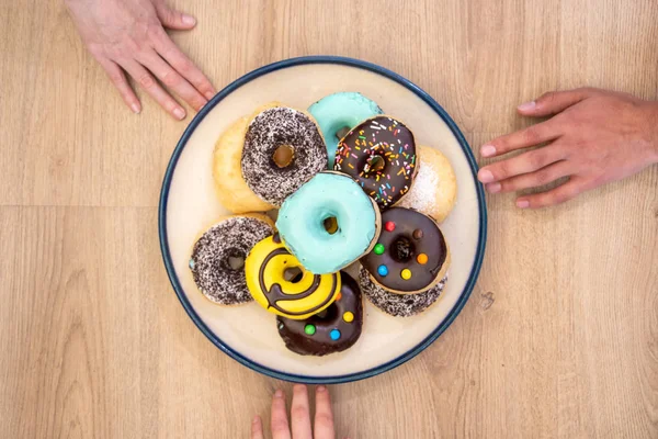 Inviting great plate full of donuts and hands sneaking in to grab one