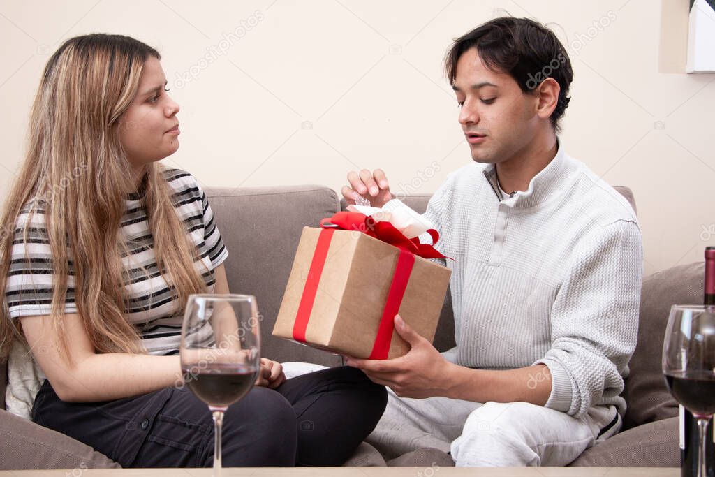 Cute young latin couple exchanging gift for valentines day