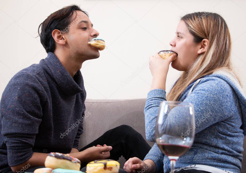 A young couple eating doughnuts