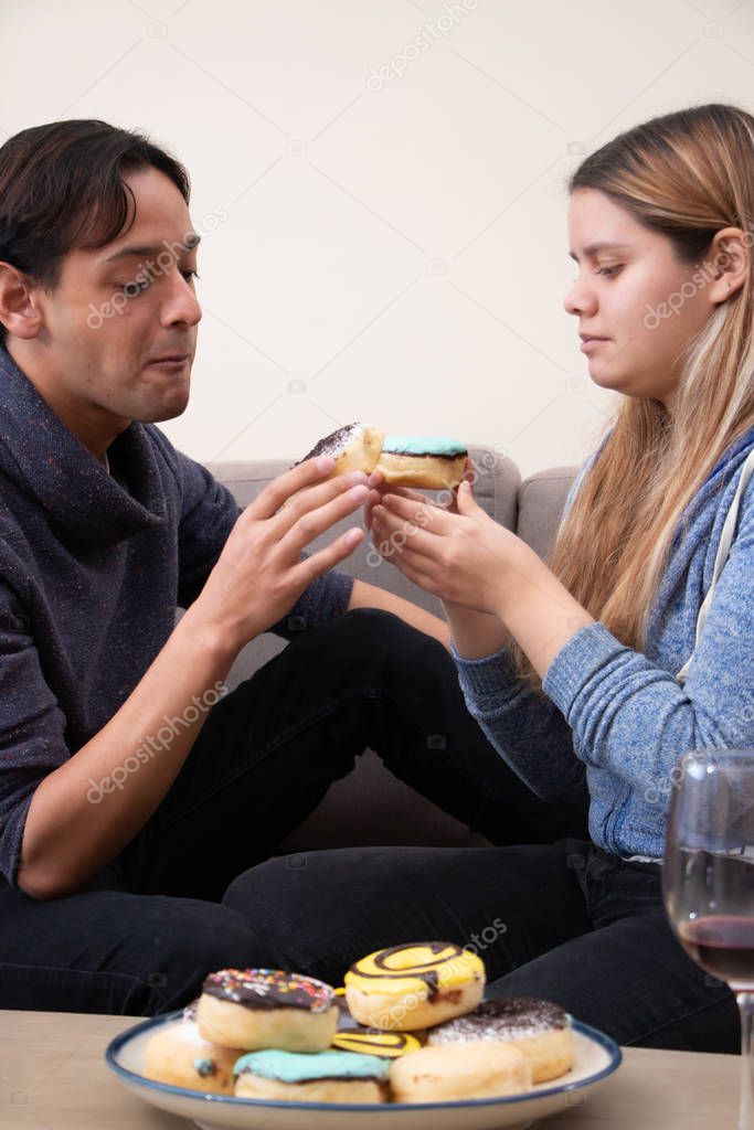 A young couple eating doughnuts