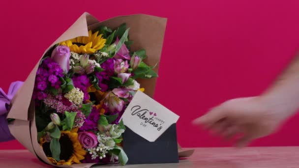 花束の横にバレンタイングリーティングカードを置く男の手 — ストック動画