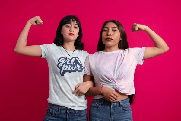 Two young empowered Mexican ladies bending their arm