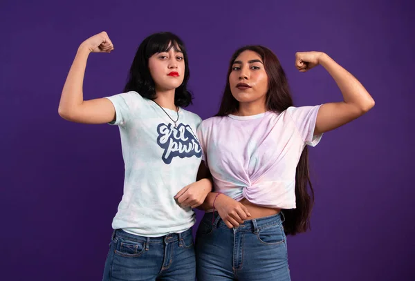 Two young empowered Mexican ladies bending their arm