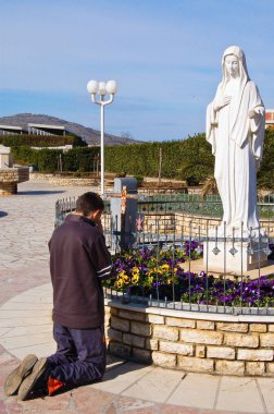 Bir adam medjogorje Madonna'nın heykeli önünde dua