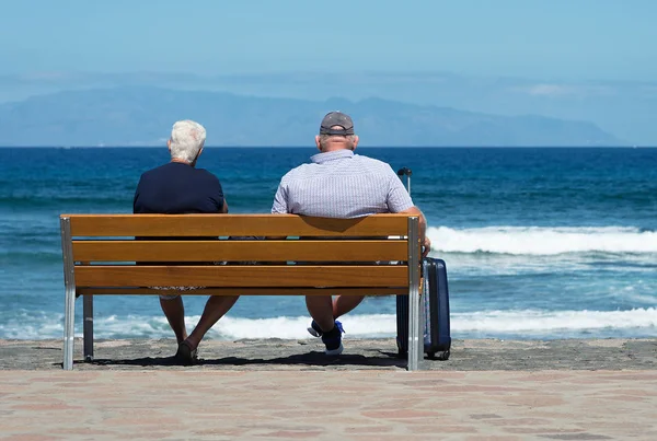 Casal de idosos esperando em um banco no mar — Fotografia de Stock