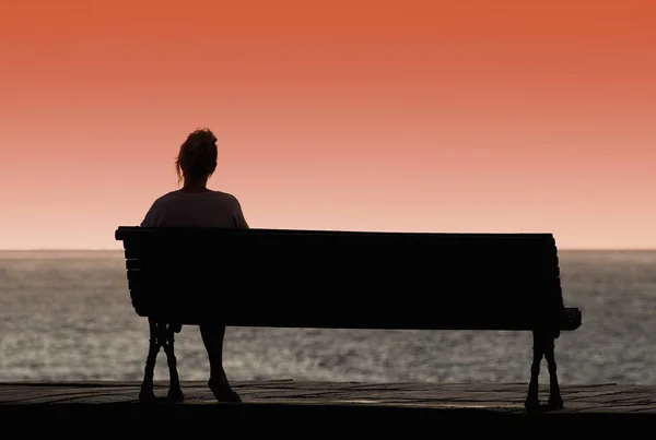 Silhouette of woman sitting alone on the bench — Stock Photo, Image