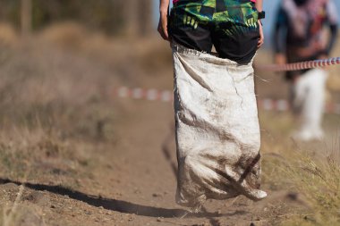 Mud race runners, playing potato sack jumping race clipart