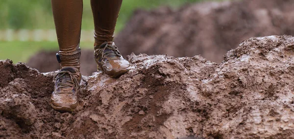 Mud race runners detail of the legs, muddy running shoes a run in the mud